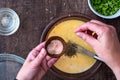 WomanÃ¢â¬â¢s hands adding a pinch of pink Himalayan salt to raw egg mixture in glass bowl, on a wood table